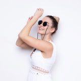 Frau mit Hypreader Sonnenbrille Aquila in Silber/Grau – moderne achteckige Brille mit Brillenband, getragen zu weißem Sommerkleid