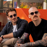 Zwei Männer tragen die schwarze Hypreader Sonnenbrille Phoenix mit runden Gläsern im urbanen Außenbereich.