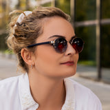 Frau mit Sonnenbrille Hypreader Taurus Gunmetal – dunkle Verlaufsgläser, runde Gunmetal-Fassung, moderner Look mit weißer Bluse.
