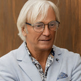 Älterer Mann mit weißem Haar trägt runde Lesebrille in Gunmetal von Hypreader – stilvoll mit hellblauem Sakko und gemusterter Hemd.