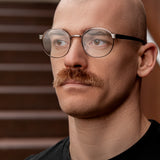 Junger Mann mit markantem Schnurrbart trägt runde Blaulichtfilter Lesebrille in Gunmetal von Hypreader – modernes, minimalistisches Design