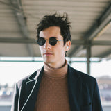 Model mit Hypreader Vela Sonnenbrille in Schwarz – urbaner Look mit runder Brille und dezentem Streetstyle-Flair.