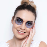 Moderne Sonnenbrille Hypreader Aquila mit achteckigen blauen Gläsern und goldfarbenem Gestell getragen von junger Frau mit Hochsteckfrisur