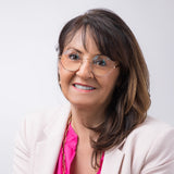 Eine Frau im hellen Blazer und pinkem Shirt trägt die Hypreader Aquila rosegold. Die Brille ergänzt ihren eleganten Look mit einem Hauch Retro-Charme – perfekt für Business und Alltag.