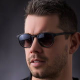 Mann mit Hypreader Aries Sonnenbrille in Schwarz vor dunklem Hintergrund – klassisch und stilvoll