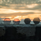 Stimmungsbild mit Hypreader Sonnenbrillen vor Sonnenuntergang – Aquila Modell mit lila Gläsern links, weitere Farben daneben auf Steinmauer