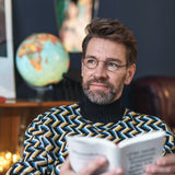 Mann mit Pullover liest ein Buch und trägt die Hypreader Gemini Blaulichtfilterbrille in grau