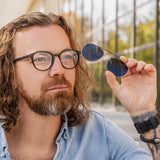 Mann mit langem Haar und Bart trägt Lupus in schwarz braun mit grauen Sonnenbrillenclip – modernes und lockeres Outdoor-Szenario