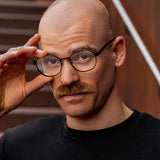 Mann im Porträt trägt Hypreader Taurus schwarze Lesebrille – runder Rahmen in Schwarz, havannafarbene Bügel.