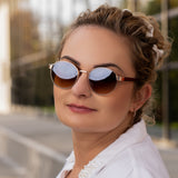 Frau mit Hypreader Sonnenbrille Taurus  in Rose, runde Roségold-Fassung mit braunen Verlaufsgläsern im Stadtambiente.