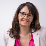 Eine Frau mit schulterlangen Haaren trägt die Aries Schwarz – die Brille fügt sich stilvoll in ihr feminines Business-Outfit ein.