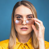 Junge Frau mit orangefarbener Hypreader Libra Sonnenbrille vor blauem Hintergrund – stylisches Modelbild mit Blickkontak