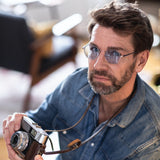 Mann mit silber-blauer Hypreader Libra Sonnenbrille und Kamera in der Hand – Lifestyleaufnahme
