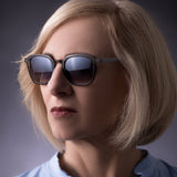  Frau mit blonder Bobfrisur trägt die Hypreader Sonnenbrille Orion in Grau Transparent mit Verlaufsgläsern