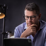 Stimmungsbild mit Mann in schwarzer Hypreader Orion Brille beim Arbeiten am Tablet – konzentriert und fokussiert.