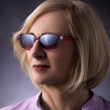 Eine Frau trägt die Hypreader Pyxis Rot Sonnenbrille in einer Studioumgebung. Das Modell wirkt elegant und gleichzeitig selbstbewusst durch die Kombination aus transparentem Rot und dunklen Gläsern.